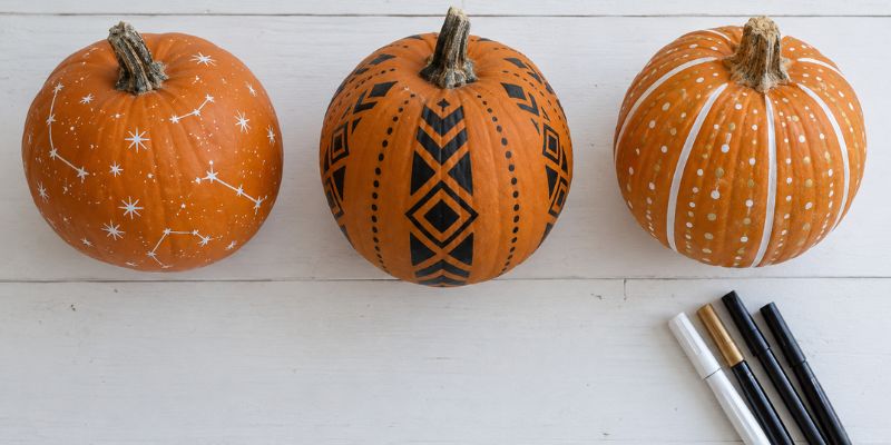 pumpkins decorated with paint markers beside a set of markers